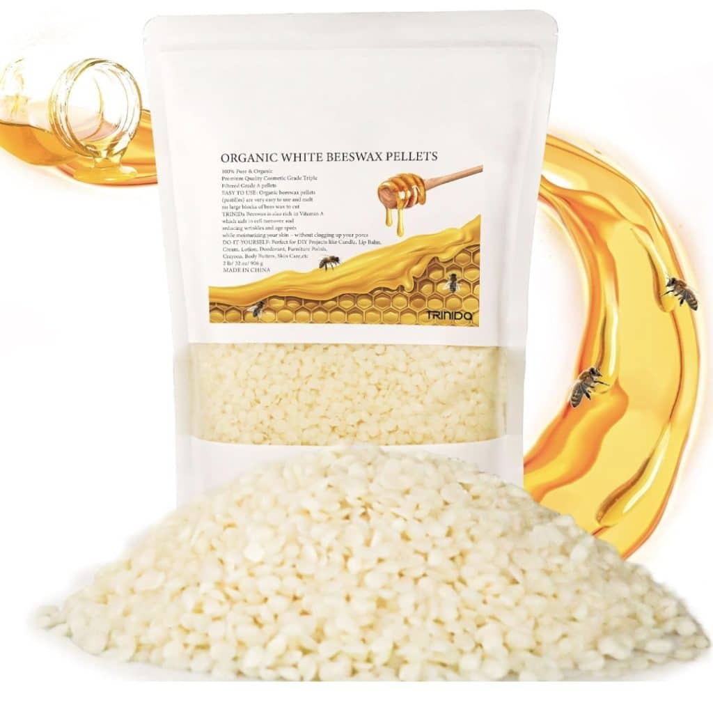 A package of organic white beeswax pellets, perfect for crafting candles with dried flowers, is labeled with product details. In the background, a honey dipper drips honey, accompanied by illustrations of honeycomb and bees. A pile of beeswax pellets is spread in front of the package.